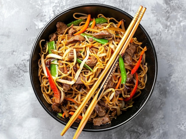 Photo a top view of a traditional asian dish on a black bowl with two chopsticks bright tonality