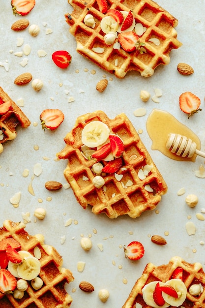 Top view traditional Belgian waffle with fresh fruit, maple syrup and nuts. Flat lay.