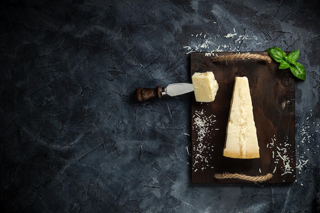 Photo top view of triangular piece of hard cheese on wooden cutting board