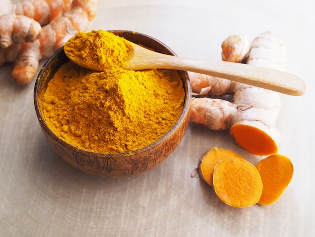 Top view of turmeric powder, curcuma and turmeric root sliced on wooden table