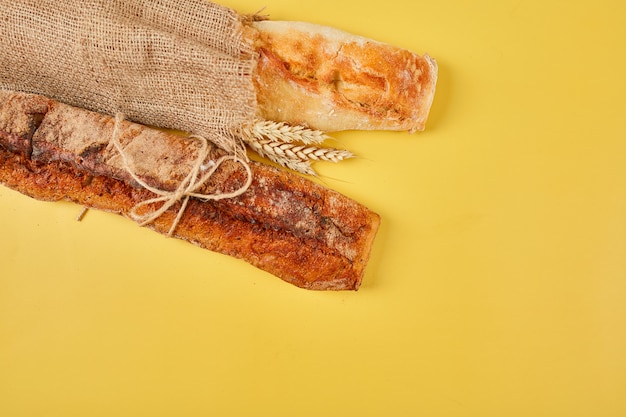 Top view of two baguette bread on a yellow surface