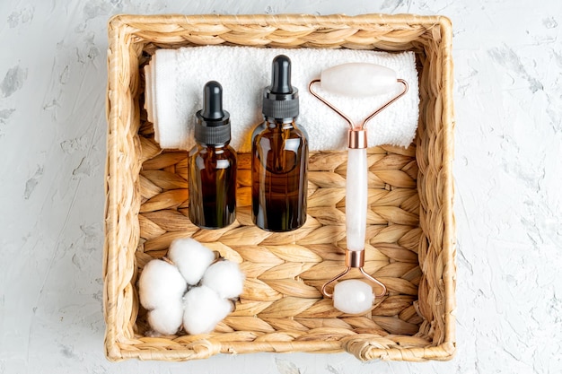 Top view of two dark glass dropper bottles with natural beauty oil and rose quartz stone massage roller for toning the skin Set for home treatment procedures