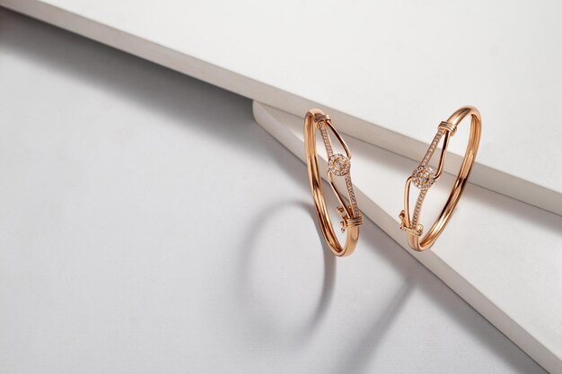 Top view of two golden bracelets on white dramatic background with copy space