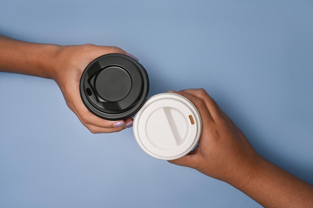 Top view of two hands holding coffee on blue background