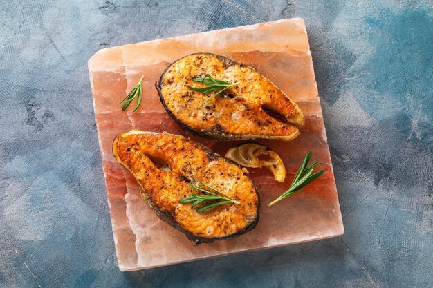 Top view of two salmon steaks cooked on a Himalayan salt slab