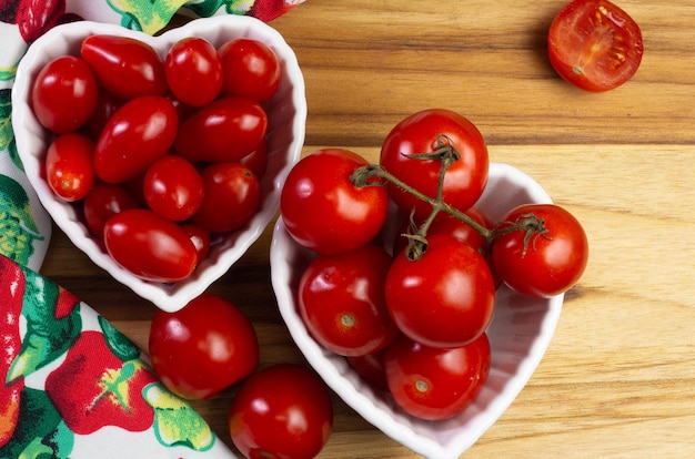 Top view of Two types of tomato inside a white bowl on a wooden table