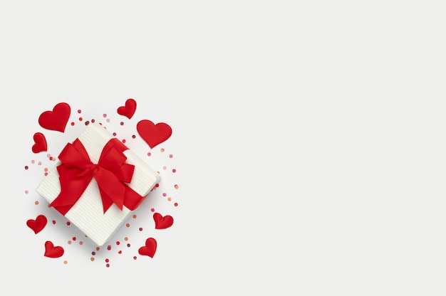 Top view of valentine's day concept with copy space. Gift box with many little hearts and confetti on white background.