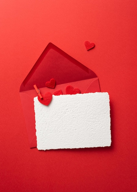 Top view Valentines Day greeting card mockup with envelope on a red background and hearts. Flat lay with copy space