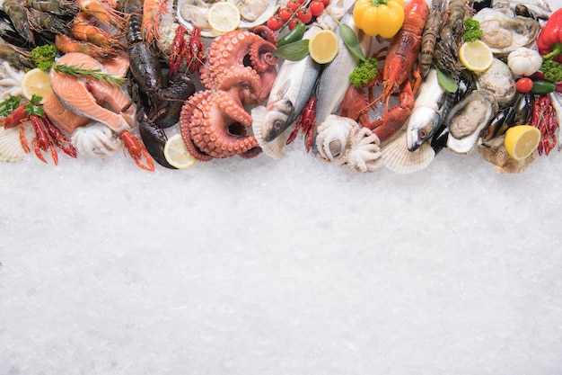 Top view of variety of fresh fish and seafood on ice with copy-apace