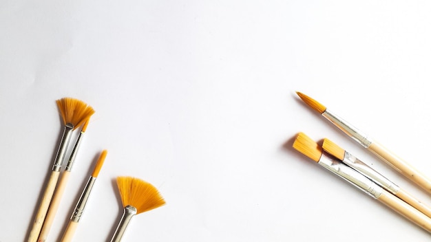 Top view of a variety of paint brushes on a white background with room for text. Creative postcard