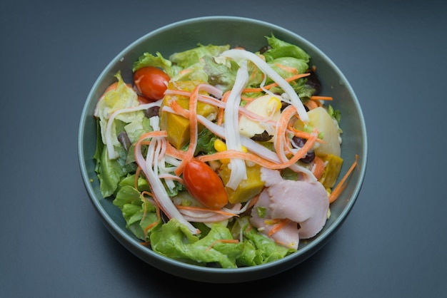 Top view of vegetable salad with ham, crab stick, apple and sweet corn.