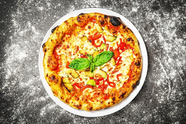 Top view of vegetarian pizza with zucchini and pepper on dark background