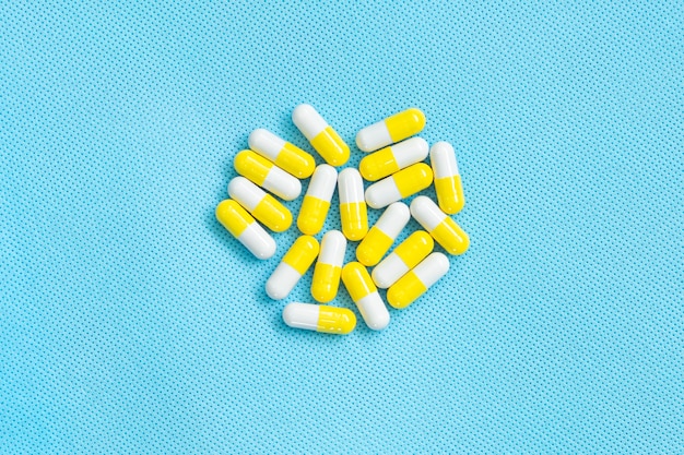 Top view of vitamin supplements. Medical concept. yellow-white pills on blue background