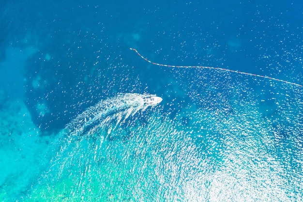 Top view of a white boat sailing in the blue sea