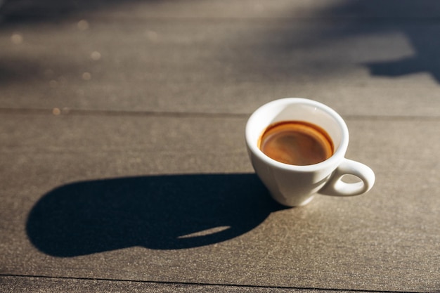 Top view white cup of espresso coffee in on the table sunlight shadow from the cup