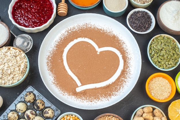 top view white flour with nuts seeds cereals raisins and jelly on dark background cake breakfast food pie dust bake cook dough heart