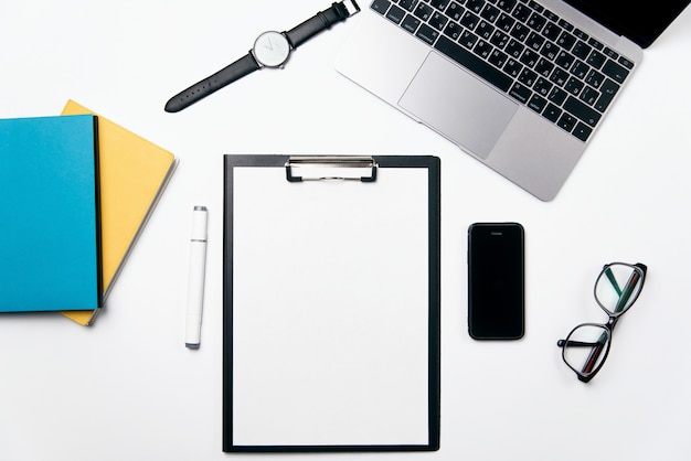 Top view white office desk with laptop, phone, notebook, clear blank of paper with free copy space and supplies, flat lay background.