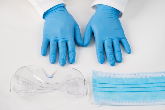 Top view on a white surface sterile blue gloves for examinations of patients plastic glasses and a protective mask from diseasesmedical content for hospitals and clinics