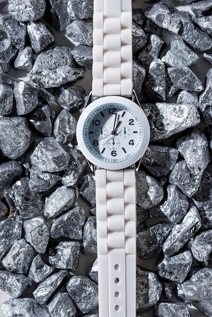 Top view of white watch with clock hands on stones