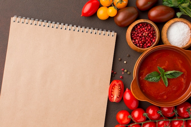 Top view of winter tomato soup in bowl with notebook