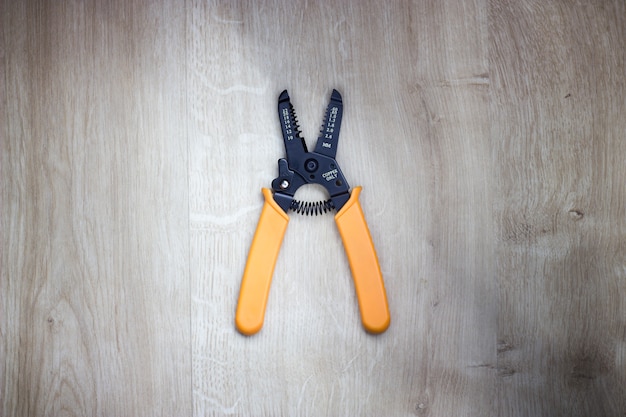 Top view on wire stripper tool. Wire stripper pliers isolated on light wooden background.