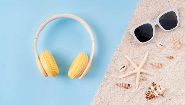 Top view of wireless headphones and camera sunglasses on sandals with blue background