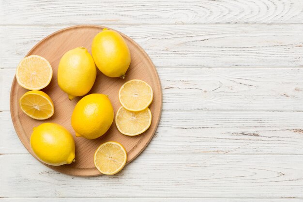 Top view with copy space for fresh and ripe lemons on cutting board Healthy food background Elegant background of lemon and lemon slices with squeezer colored background