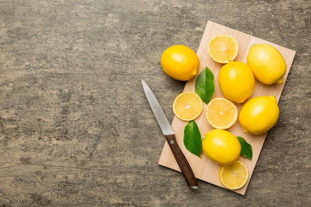 Top view with copy space for fresh and ripe lemons on cutting board Healthy food background Elegant background of lemon and lemon slices with squeezer and knife colored background