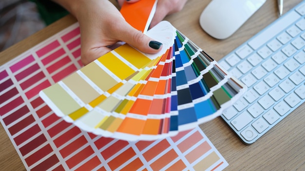 Top view of woman designer holding fan of colourful samples in hand designer searching proper