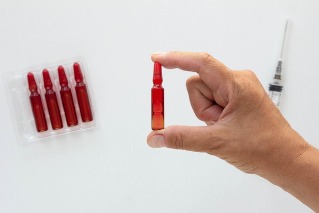 Top view of woman hand holding ampoule with vitamin group B for injection on the white background