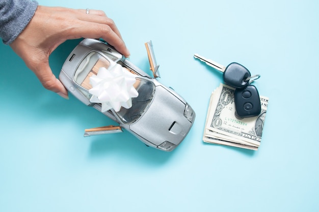 Top view of woman hand with car, key and money on blue color background