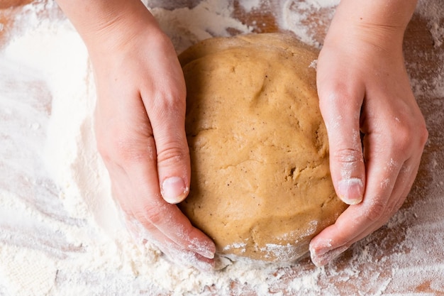 Top view of woman hands kneading the dough for buns pie cookies or pastry on the wooden desk process