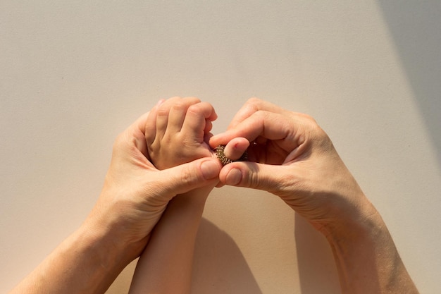 Top view of woman hands putting on massage ring Su-Jock on child finger on the white background