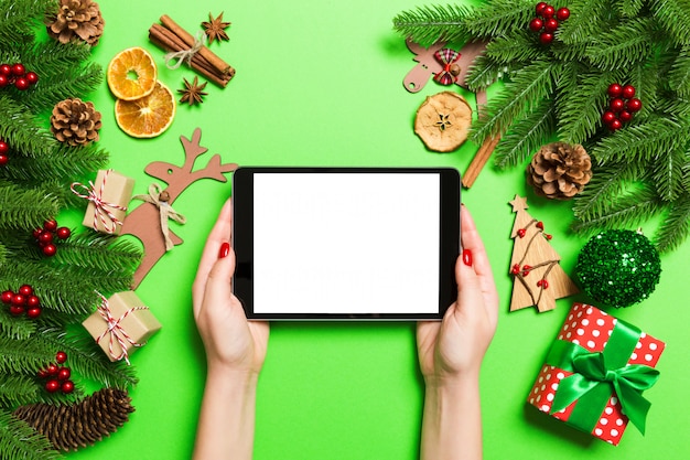 Top view of woman holding tablet in her hands on green background 