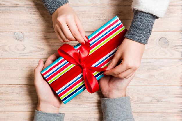 Top view of a woman and a man giving and receiving a present on wooden background Love and relationship concept Close up