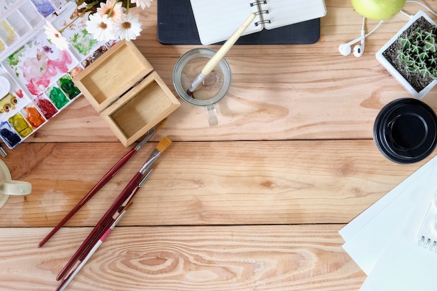 Top view wood desk of an artist with lots of stationery object.