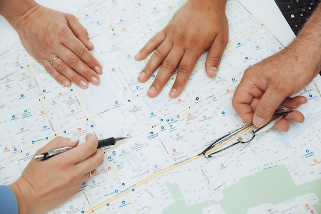 Photo top view of a wooden conference table with charts and graphs papers on the table and the hands of business people folded together applauding a concept for a business meeting