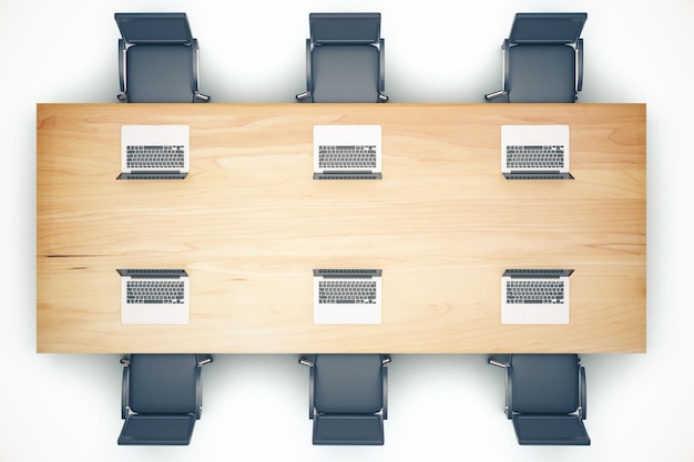 Top view of wooden meeting table with chairs and laptop