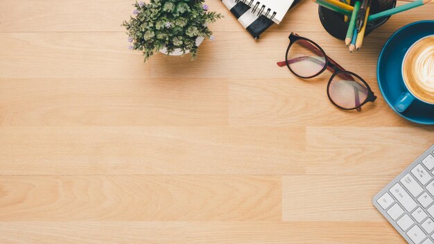 Photo top view wooden office desk with keyboard computer cup of coffee pen eyeglass and notebook copy space mock upx9