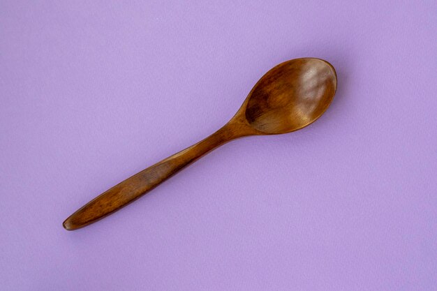 Top view Wooden spoon on pastel purple background