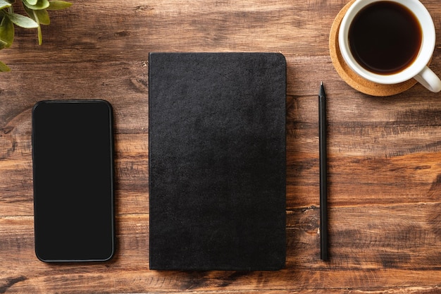 Top view working desk with close notebook and mobile phonecoffee cup on wooden table background