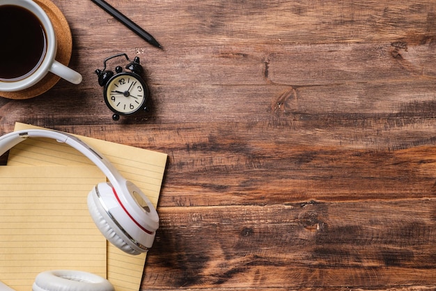 Top view working desk with headphone and notebook coffee cup on wooden table background