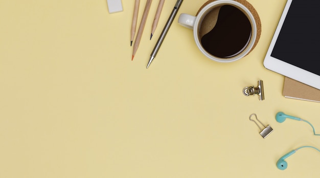 Top view workspace office supplies mockup with tablet, hot coffee cup, books and accessories isolated on yellow background, Overhead view with copy space, Workspace for designer concept