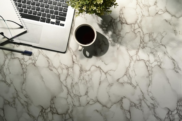 Top view workspace with laptop coffee notebook on marble table