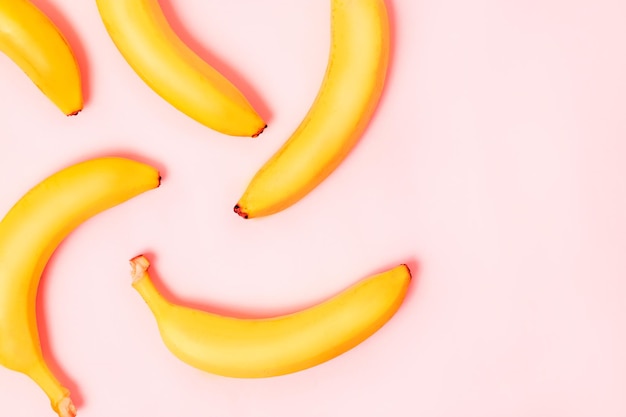 Top view of yellow, ripe bananas on a pastel pink background with copy space. Flat lay, closeup