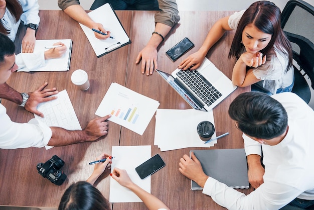 Top view of young business people that working together with documents and laptop in the modern office.