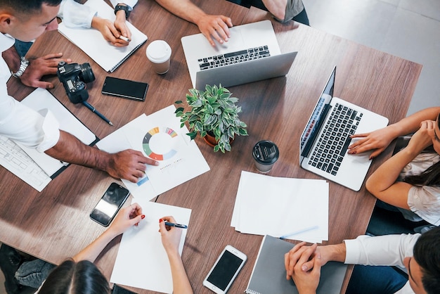 Top view of young business people that working together with documents and laptop in the modern office.