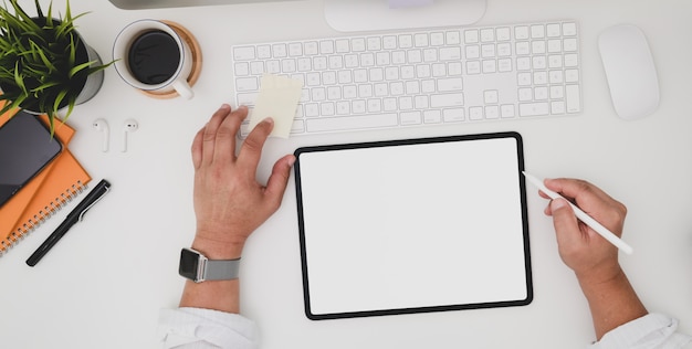 Top view of young businessman writing on blank screen tablet in modern office room