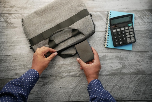 Top view of young man putting office stationary in his bag