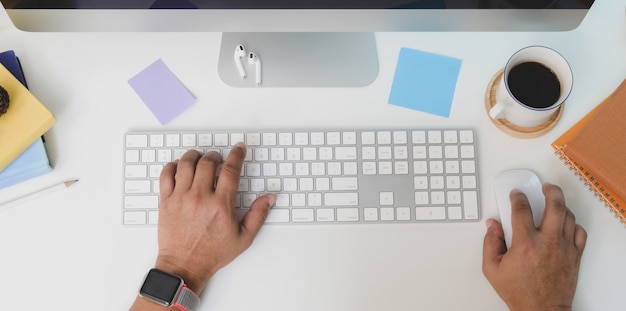 Top view of young man typing on keyboard computer while working on his project 